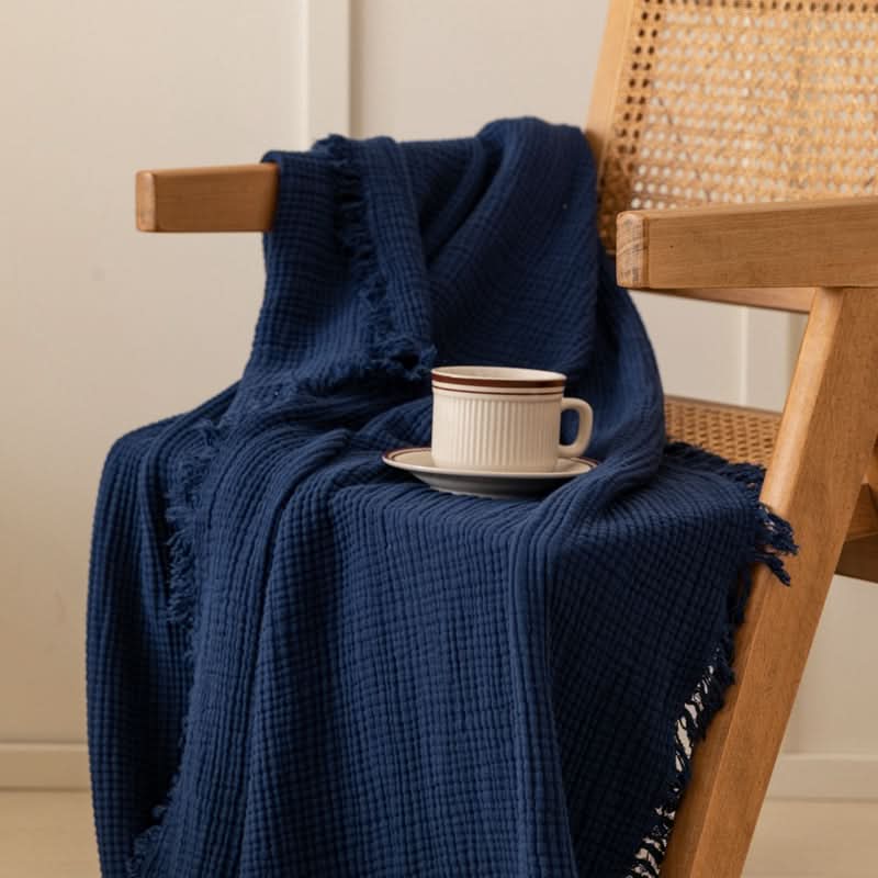 Navy Four-Layer Waffle Weave Cotton Throw Blanket draped on a wooden chair with a mug.